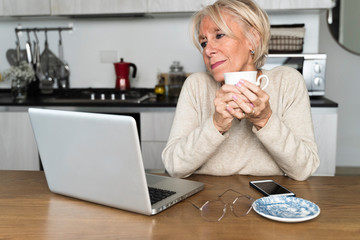Adult woman drinking coffee watching the laptop