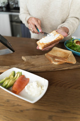 woman spreading soft cheese on a toasted bread