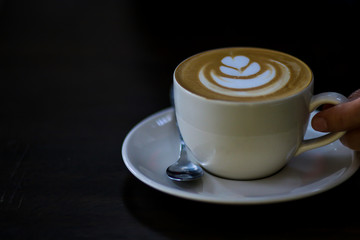 Latte coffee cup at coffee shop. Hand hold cup of coffee.