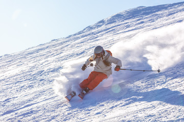 Girl On the Ski. a skier in a bright suit and outfit with long pigtails on her head rides on the track with swirls of fresh snow. Active winter holidays, skiing downhill in sunny day. Woman skier