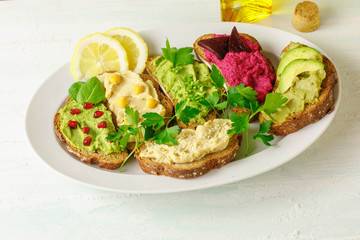 Different kinds of dips bread with humus. Traditional with chickpeas and sesame seeds , herbs with spinach leaves, avocado and beetroot hummus, 