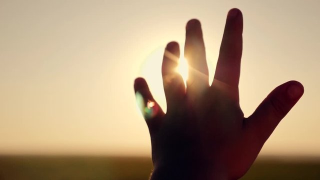 Female hand close-up at sunset. Sun rays through fingers