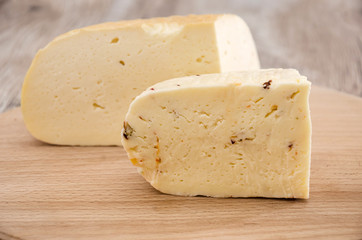 two pieces of hard cheese on a wooden background. Ukrainian cheese.