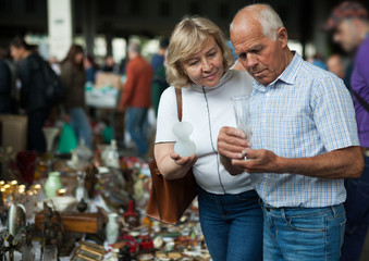 Portrait of positive adult family looking for vintage goods at flea market