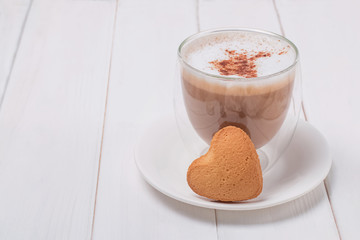 Cup of coffee and sweet heart shaped bisquit on white table