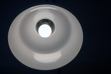 a bright white lamp shines on the ceiling in a dark room