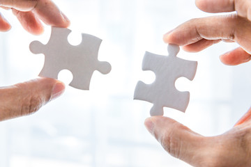 Hand holding two pieces of jigsaw connecting couple puzzle