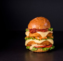 Hamburger with a double serving of meat, tomatoes, salad, onions on a wooden board in a restaurant.Copy space