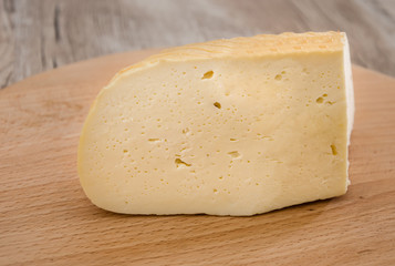 piece of hard cheese on a wooden background. Ukrainian cheese. Close-up.