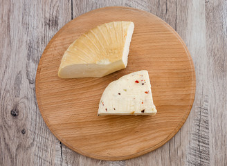 two pieces of hard cheese on a wooden background. Ukrainian cheese.