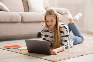 Blonde girl student studying at home, laying on floor