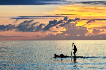 Photo sur Plexiglas Plage blanche de Boracay Silhouette of a woman laying on a paddle board, with a man paddling while standing. A peaceful scene along the White Beach of Boracay at sunset