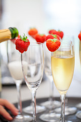 Sparkling wine or champagne and strawberry on a blurry background being poured out from the bottle during some sort of festivity or celebration such as a wedding, borthday or newyear