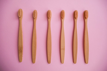wooden bamboo toothbrushes on pink background