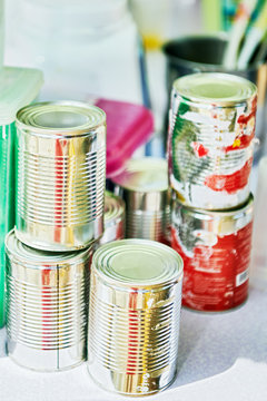 Close-up of damaged and peeled tin cans containing condensed milk, used in mixing milk shake, placed on a table next to kitchen utensils