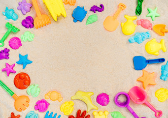 Flatlay playground, sandbox and multi-colored plastic toys. Frame for text. Layout for children's topics about games and relaxation on the beach.
