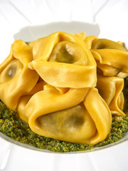 Fresh Italian traditional tortelloni with pesto sauce, on an elegant white plate