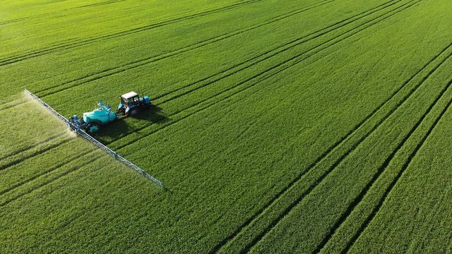 KRASNODAR, RUSSIA - MAY 24, 2019: AERIAL VIEW Agricultural machinery BELARUS tractor with an irrigation trailer BERTHOUD rides through the green field of agricultural crops and carries out irrigation.
