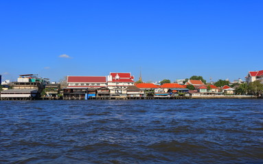 Fototapeta na wymiar Bangkok cityscape shows Thai style houses and buildings on waterfront along Chao Phraya river, view from tourist boat