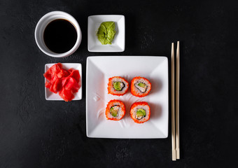 Fototapeta na wymiar rolls with caviar, avocado, cheese and rice on a white plate, sticks, sushi, soy sauce, wasabi, ginger