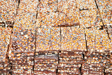 Peanut brittle bars covered with sesame seeds laying for sale on a table at a market in the Philippines