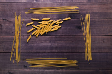 Dry pasta - spaghetti and penne. Types and shapes of uncooked italian macaroni on wooden background.