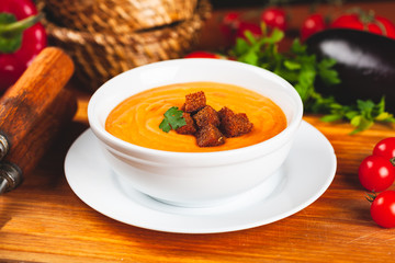 Vegetarian autumn pumpkin cream soup served in a white bowl with croutons.