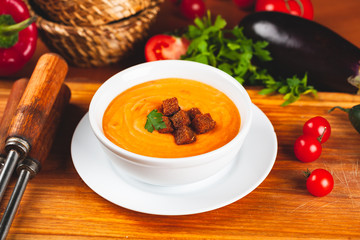 Vegetarian autumn pumpkin cream soup served in a white bowl with croutons.
