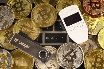 WROCLAW, POLAND - JANUARY 28, 2020: Physical version of Bitcoin (BTC), Trezor and Ledger (cryptocurrency hardware wallets) and enter button.