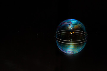 Colorful soap bubble on a black mirrored surface