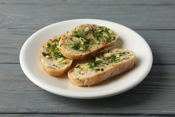 Plate with toasted garlic bread on wooden background, close up