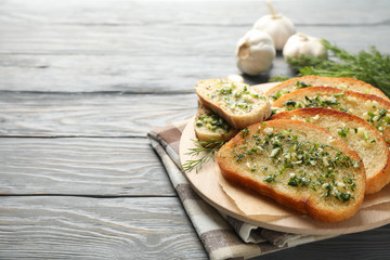 Circle board with toasted garlic bread on wooden background, close up