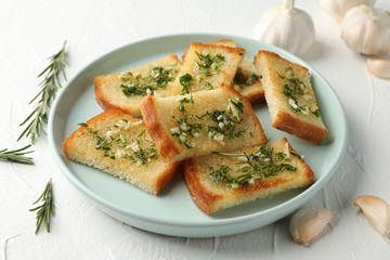 Plate with toasted garlic bread on white background, close up