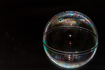 Colorful (rainbow) soap bubble on a black mirrored surface