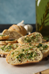 Baking paper with toasted garlic bread and oil on grey background, close up