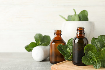 Mortar, medical bottles and mint on grey table, close up