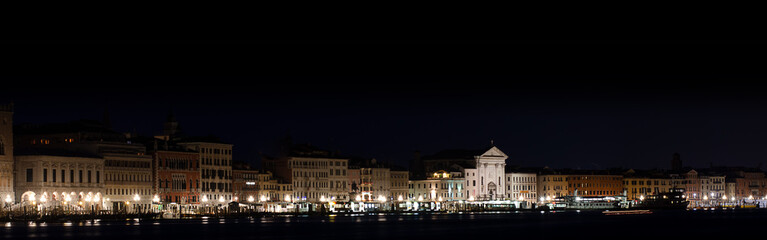 Fototapeta na wymiar Long horizontal BANNER.Cityscape of Venice at night on black. The city lights punctuate the Venetian night.