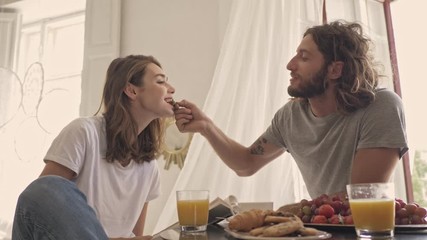 joyful lovely couple having dinner together while sitting by the table on kitchen at home - Powered by Adobe