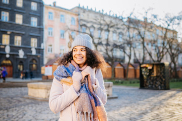 Fototapeta premium The portrait of a young African-American female leaning against an iron fence outdoors in the park beautiful curly-hair biracial girl in sunglasses