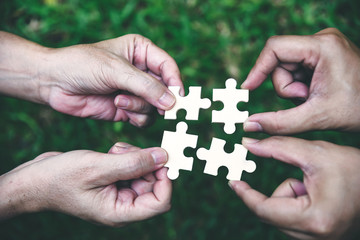 Stakeholders business team holding jigsaw puzzle as a team building and organization connection symbol. Teamwork and connection conceptual.