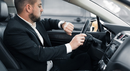 Handsome caucasian businessman driver inside in vehicle  with coffee and gadget and check mail and talking with partners