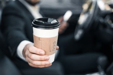 Handsome caucasian businessman driver inside in vehicle  with coffee and gadget and check mail and talking with partners