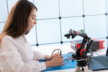 A young woman writes an algorithm for the robot arm. Science Research Laboratory for Robotic Arm...