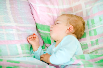 Adorable little baby girl sleeping in bed. Calm peaceful child dreaming during day sleep. Beautiful baby in parents bed. Sleeping together concept.