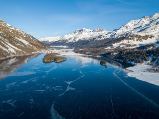 Aerial image of the Chaviolas and Chaste islets on the frozen lake of Silsersee in St. Moritz, Switzerland