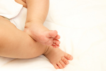 Fototapeta na wymiar Legs of infant on the white blanket, bedroom, blurred background