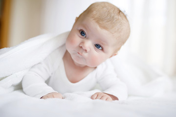 Baby girl wearing white towel or winter overal in white sunny bedroom