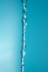 water stream pouring down on blue background copy space close up