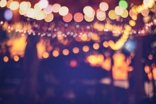 blurred bokeh light on sunset with yellow string lights decor in beach resort