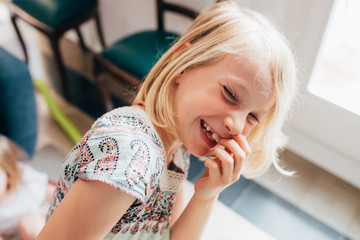 Young beautiful female child indoor at home looking camera laughing